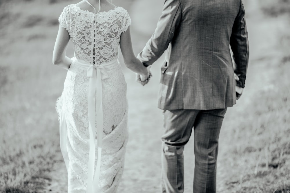 man and woman holding hands while walking on road