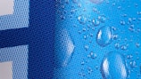 A close-up of a pixelated design with a blue color scheme and water droplets overlaid. The pattern consists of various shades of blue dots forming a gradient from light to dark. The droplets add a realistic, three-dimensional texture to the otherwise flat image.