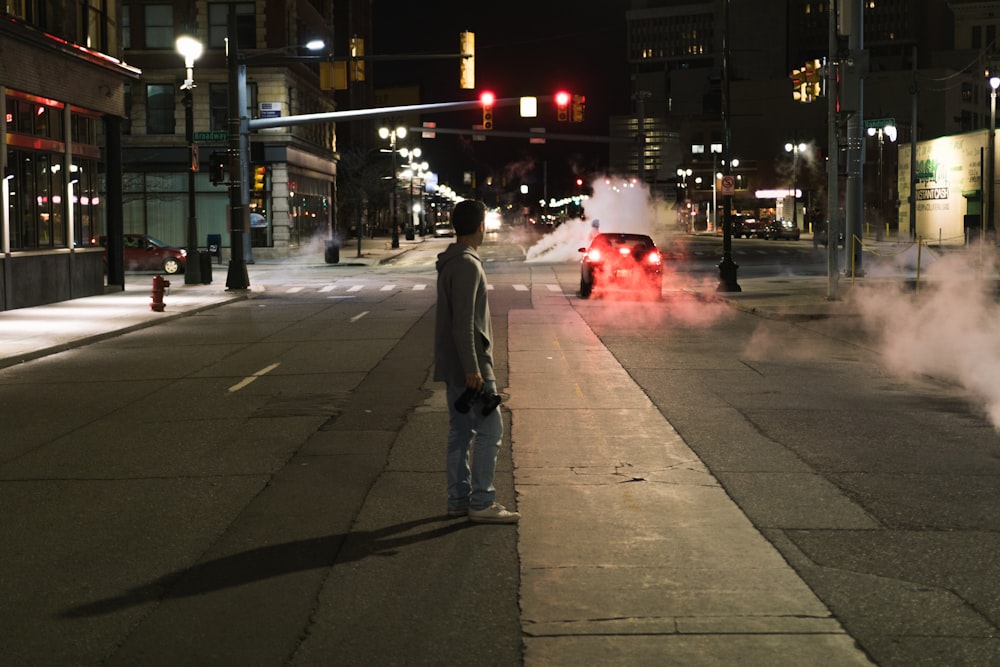 man standing on middle of street while looking at car