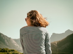 woman with sunglasses sitting on mountain during daytime