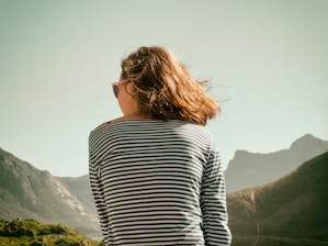 woman with sunglasses sitting on mountain during daytime