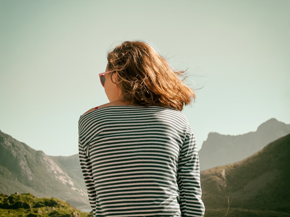 mulher com óculos de sol sentada na montanha durante o dia