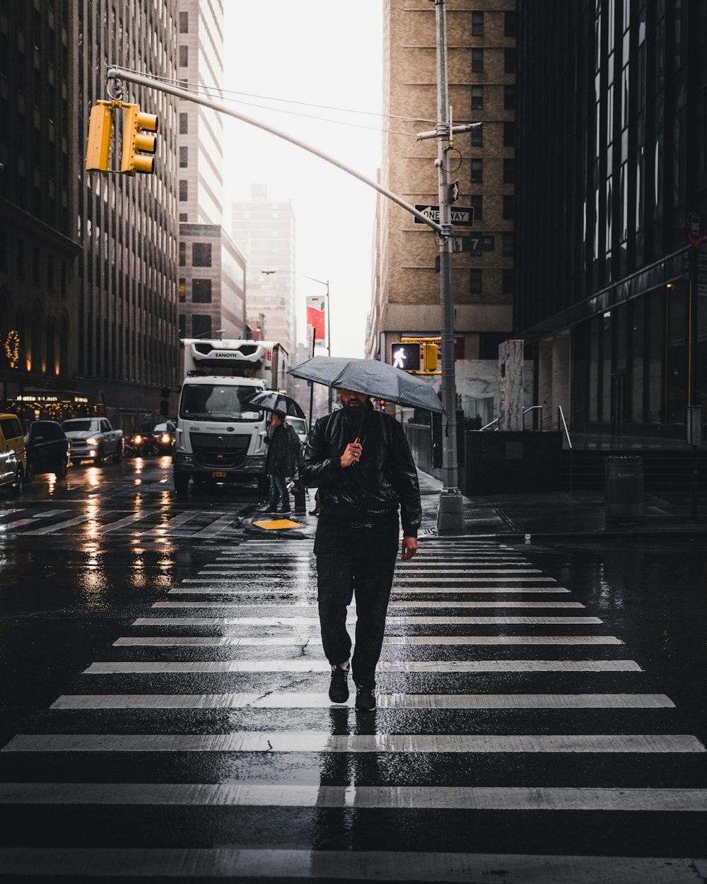 homem segurando guarda-chuva andando na faixa de pedestres