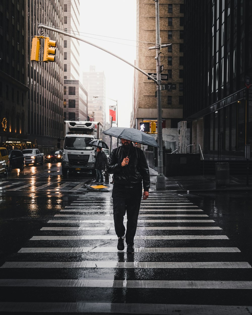 man holding umbrella walking on pedestrian lane