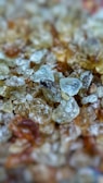 A close-up view of a collection of translucent, rough-textured crystals in various shades, giving a natural and raw appearance.