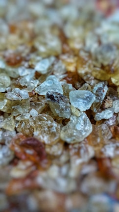 A close-up view of a collection of translucent, rough-textured crystals in various shades, giving a natural and raw appearance.
