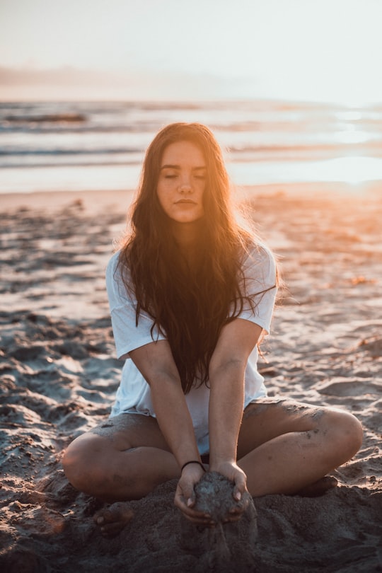 woman sitting on sand holding sands during daytime in Oceanside United States