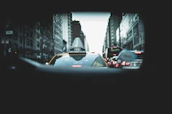 A rear dashcam lens capturing a vehicle tailgating a taxi on a busy city street.