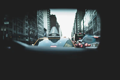 A dashcam mounted on a taxi windshield capturing a busy city street during rush hour.