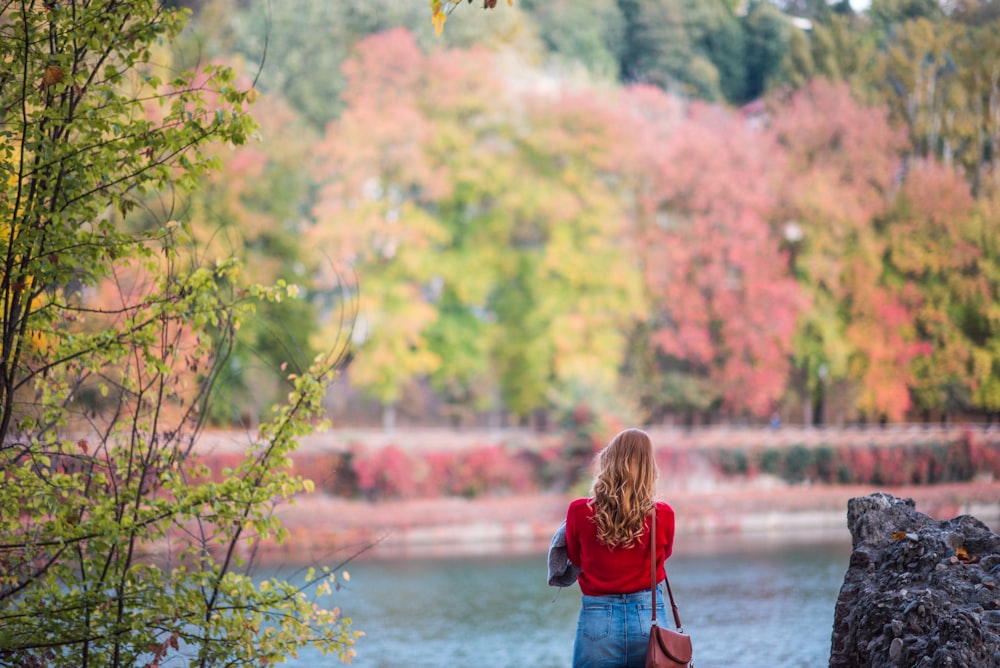 Femme en robe rouge et bleue debout devant le plan d’eau