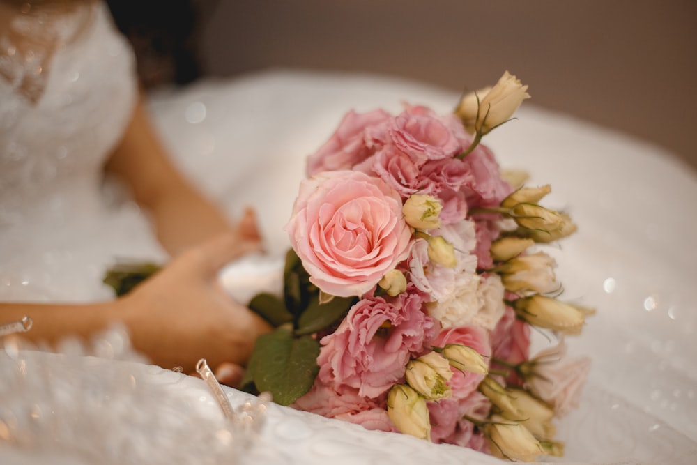 donna in abito da sposa bianco che tiene il bouquet di fiori rosa e bianchi