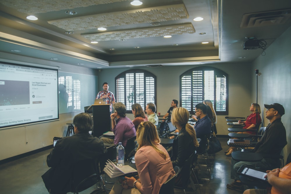 a group of people in a room with a projector screen