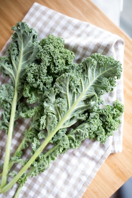 Fresh curly kale leaves ready for massaging on a wooden cutting board