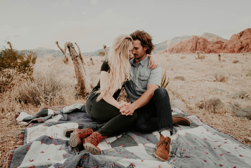 Mann und Frau sitzen auf einer Decke, während sie sich an den Händen halten