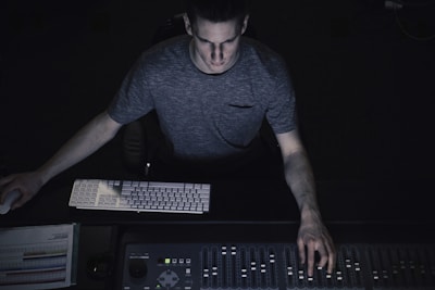 A producer adjusting levels on a mixing board with focused concentration.