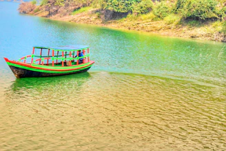 A vibrant shikara boat passing by the Lakes Crown houseboats with blooming lotus flowers in the lake.