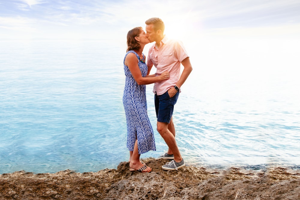 man and woman kissing near body of water