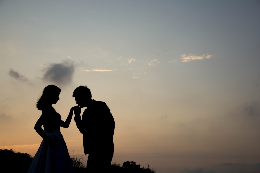 silhouette of man kissing hand of woman