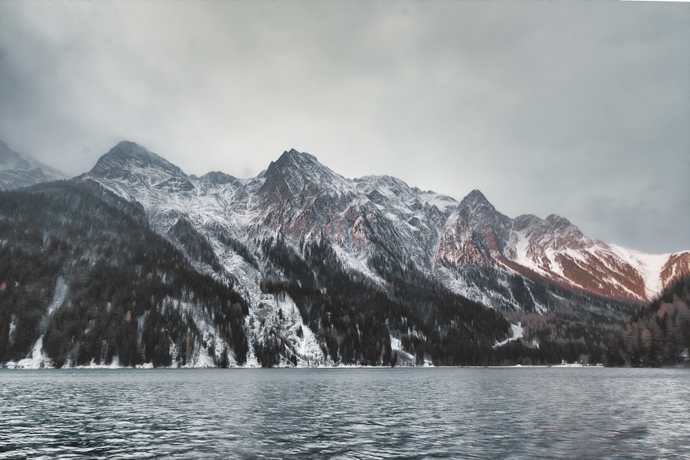 mountain covered with snow under gray clouds