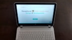 A laptop computer with a website displayed on the screen featuring the text 'Exceptional Web Application design & development'. The laptop is on a dark surface, and the website has a clean and modern design with a light background and colorful text elements.