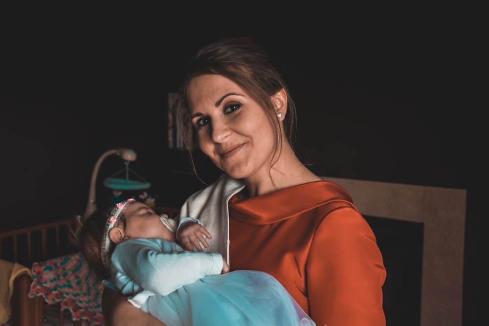 mujer sonriente que lleva a un bebé dormido