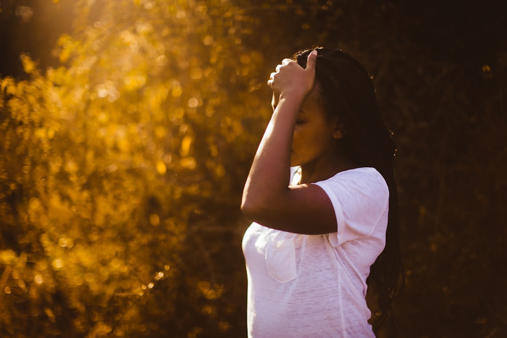 woman in white shirt holding her forehead