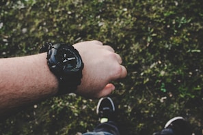 A wrist wearing a bdxsho watch paired with a casual outfit outdoors.