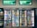 Refrigerated display cases contain a wide assortment of colorful beverages, including bottles and cans of different sizes and shapes. Shelves are neatly organized, featuring various drinks like water, soda, juice, and energy drinks. Bright lighting highlights the vivid packaging and labels.