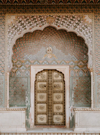 An ornate brass door set within a decorative arched wall in Jaipur, India