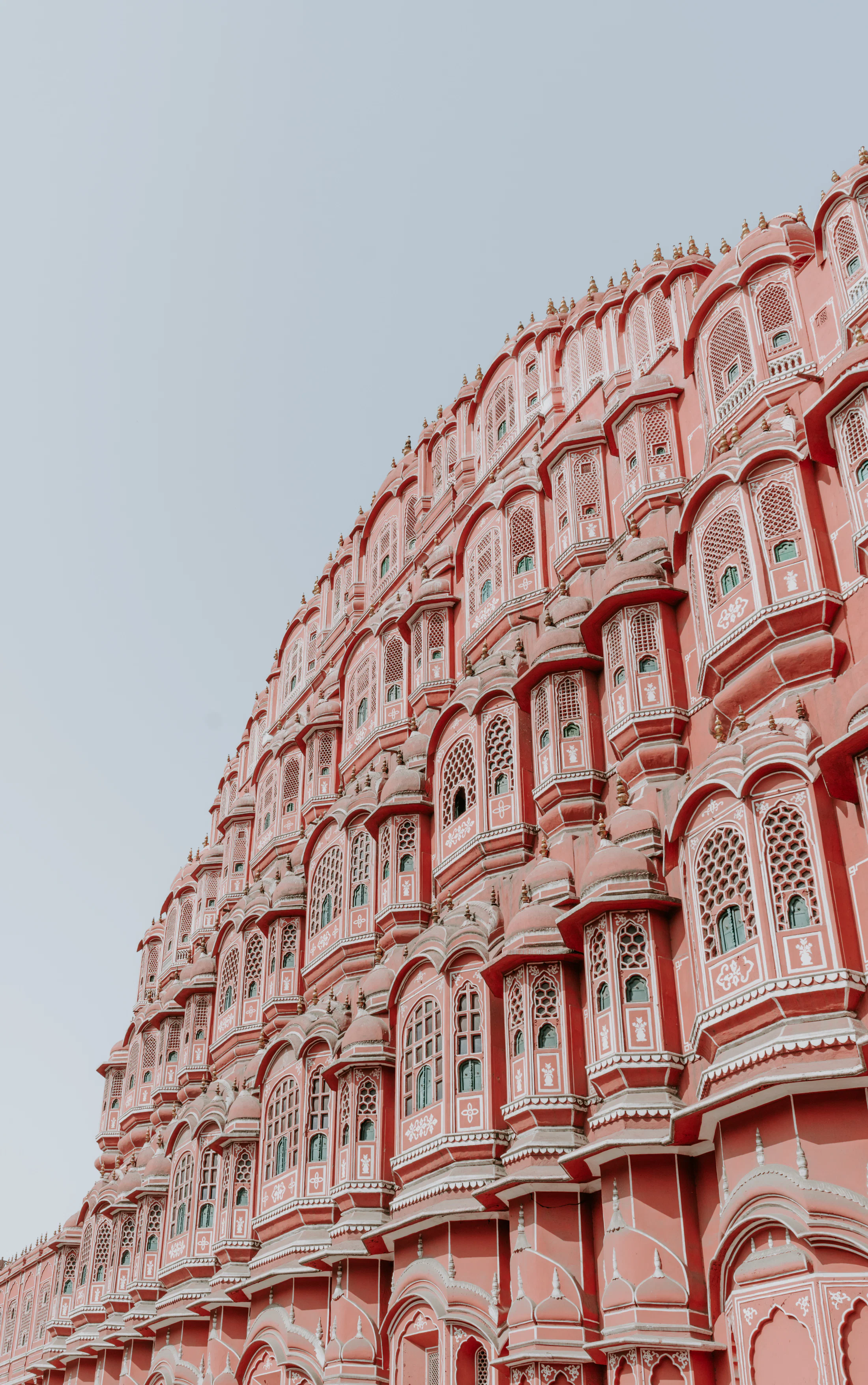 The honeycomb pink façade of the Hawa Mahal in Jaipur against a pale sky