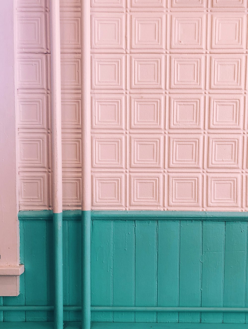 pink and green painted wall with two pipe