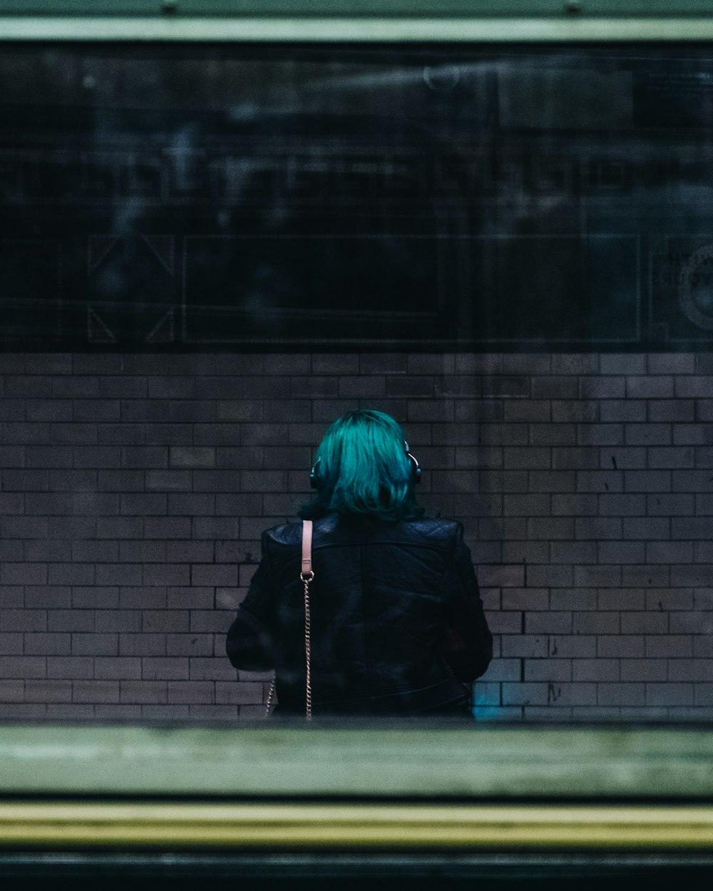 teal hair colored person standing behind glass panel