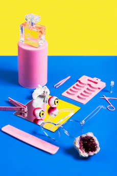 A cheerful flat lay of sunglasses, watches, and perfumes with splashes of bright colors around them.