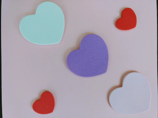 Colorful silicone molds in various shapes such as stars, hearts, and flowers neatly arranged on a wooden surface.