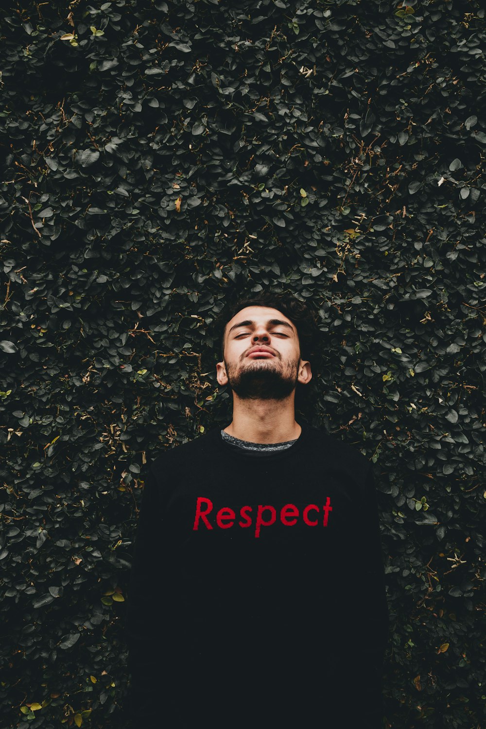 man leaning on plant wall