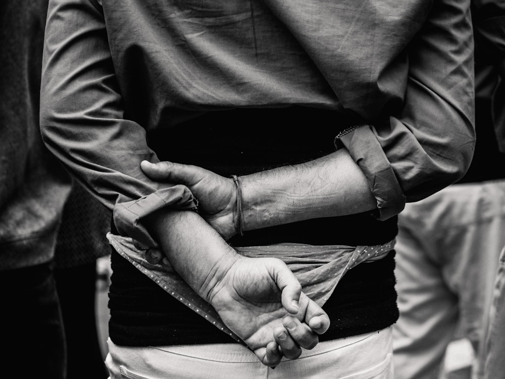 Foto en escala de grises de una persona con las manos en la espalda