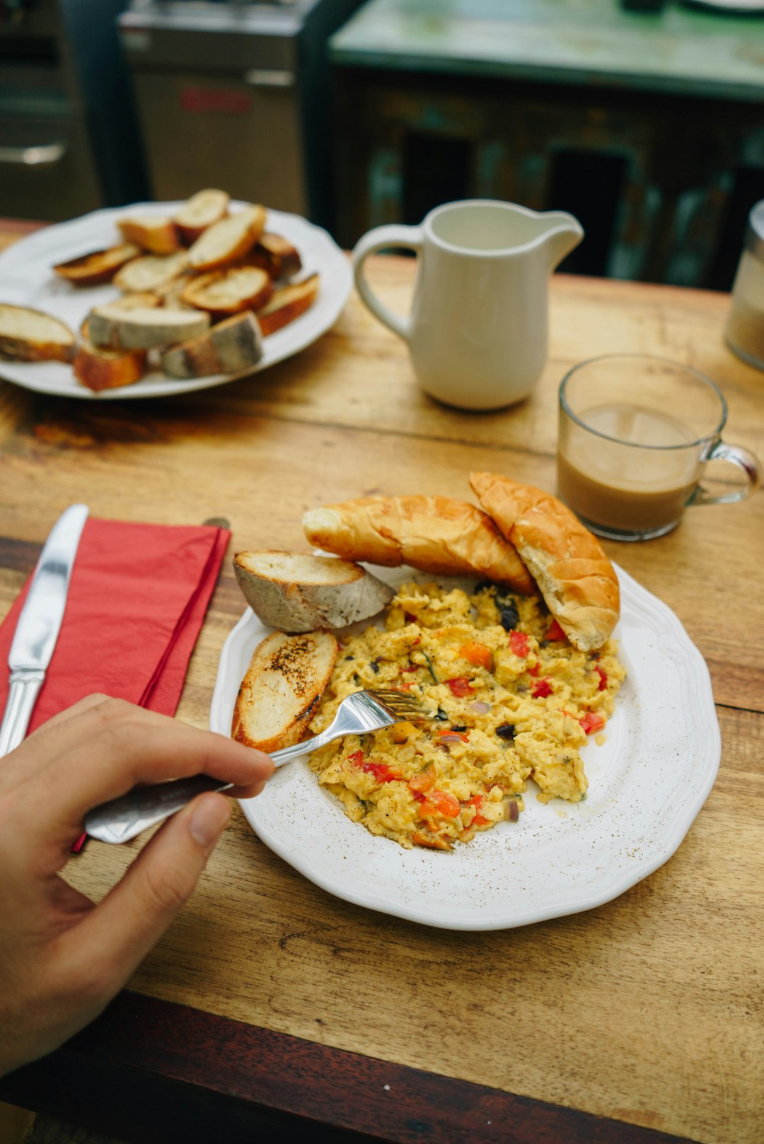 person holding fork on scrambled egg