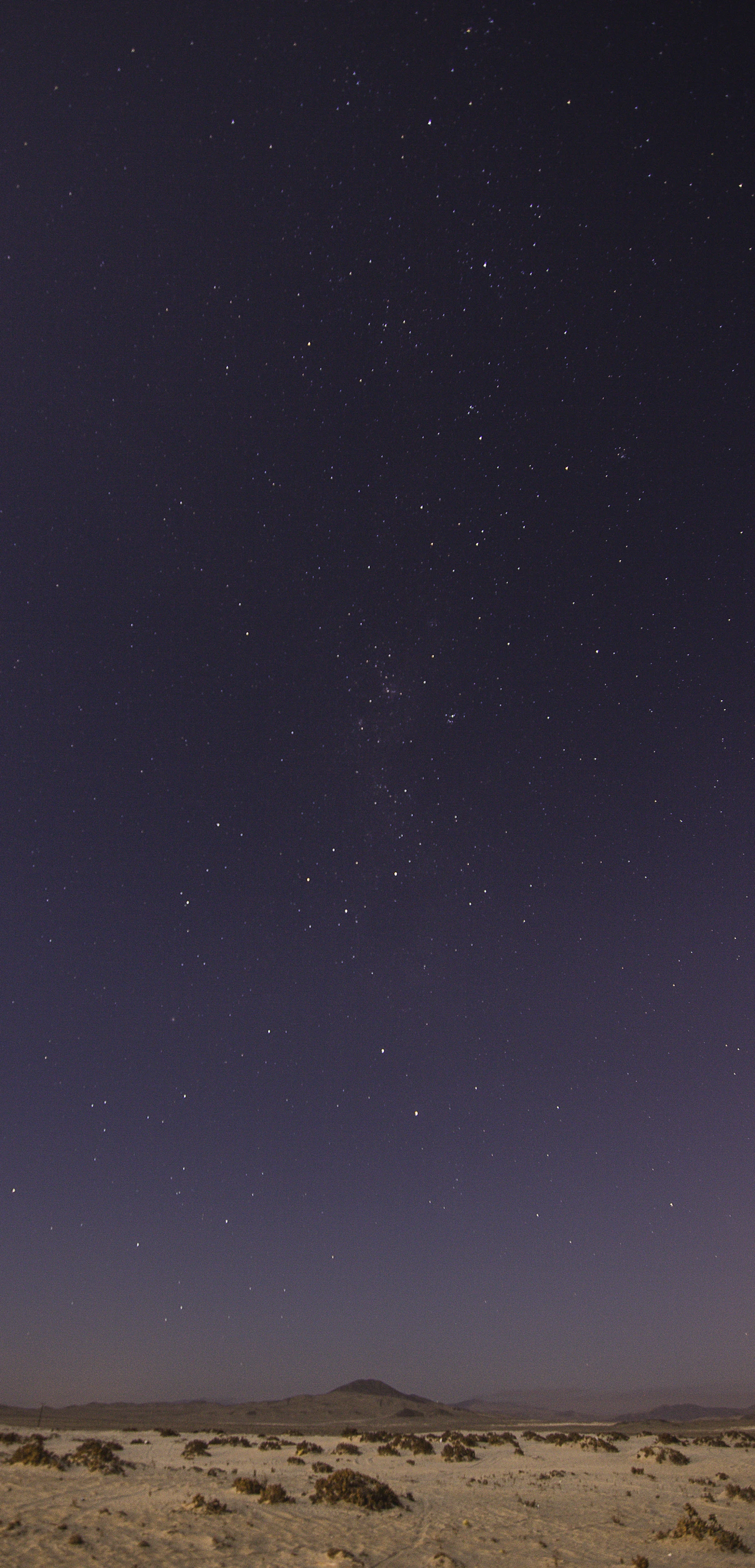 Milky Way arching across an ink-blue sky above a high desert landscape with no light pollution