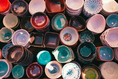 Close-up of colorful handmade ceramic bowls arranged on a wooden table bathed in warm sunlight.