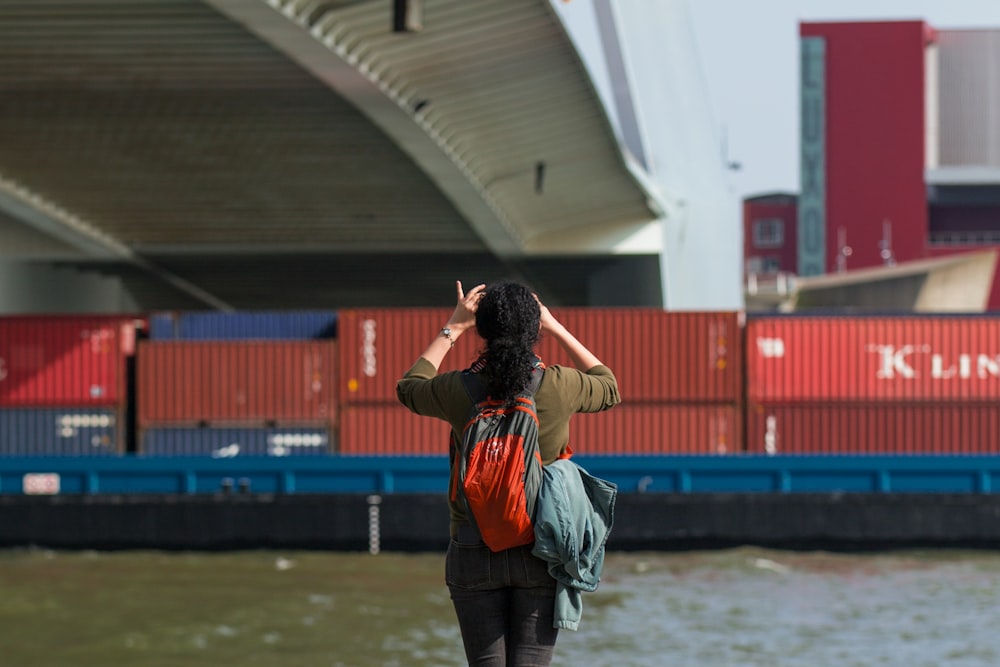 a woman with a backpack is taking a picture of a bridge