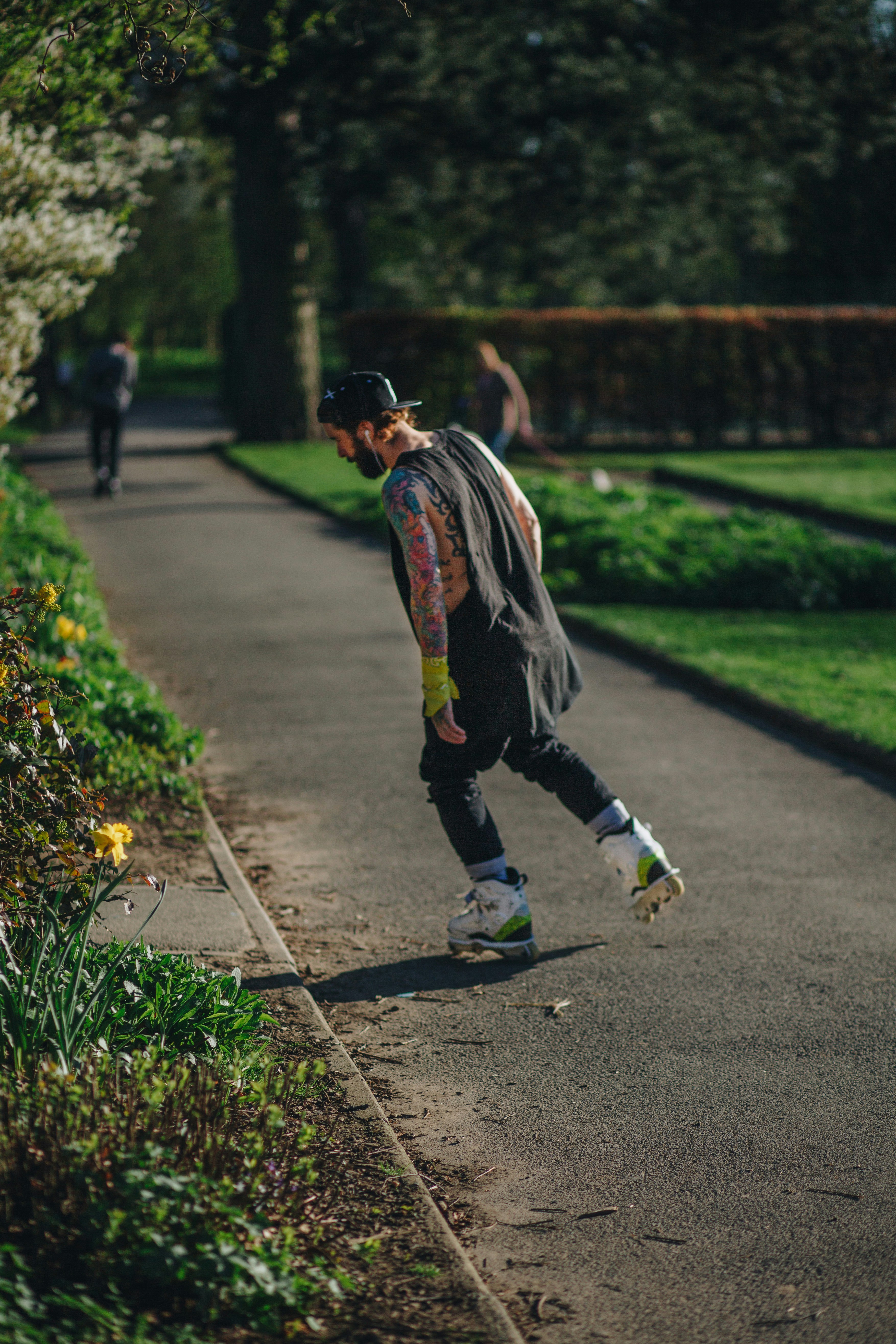 Un hombre caminando por una acera junto a un exuberante parque verde