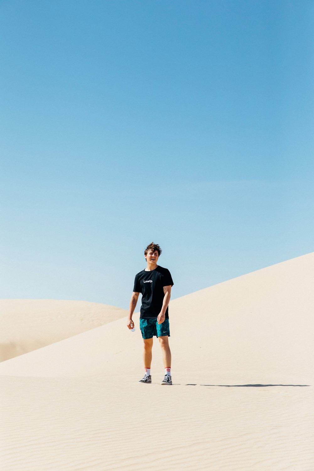 푸른 하늘 아래 사막 한가운데에 서 있는 사람