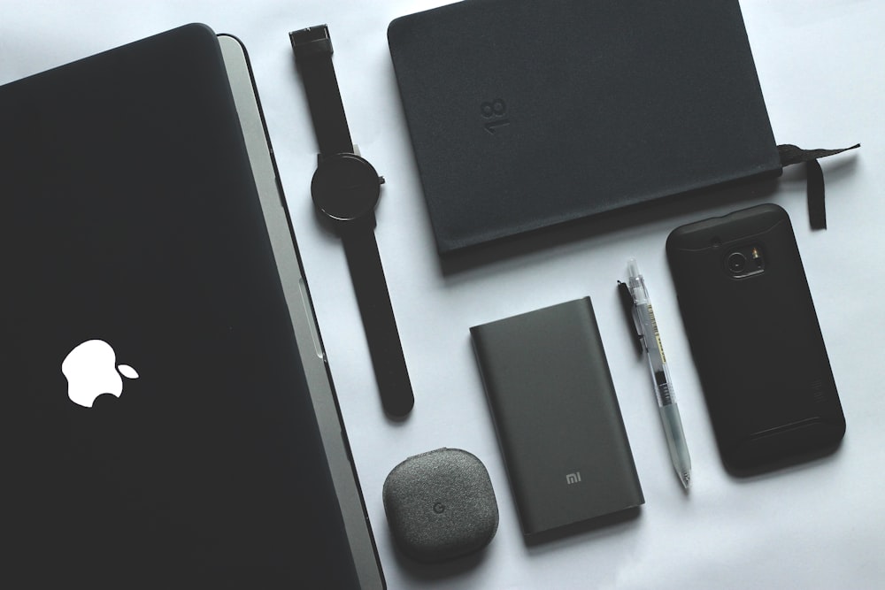 MacBook, reloj, smartphone y notebook negros