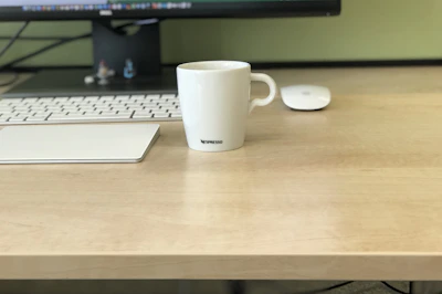 Close-up of a warm beige coffee mug beside a sleek keyboard on a clean workspace.