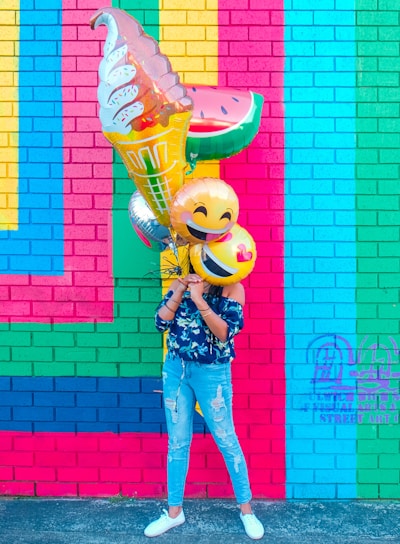 woman covering face with assorted ballons