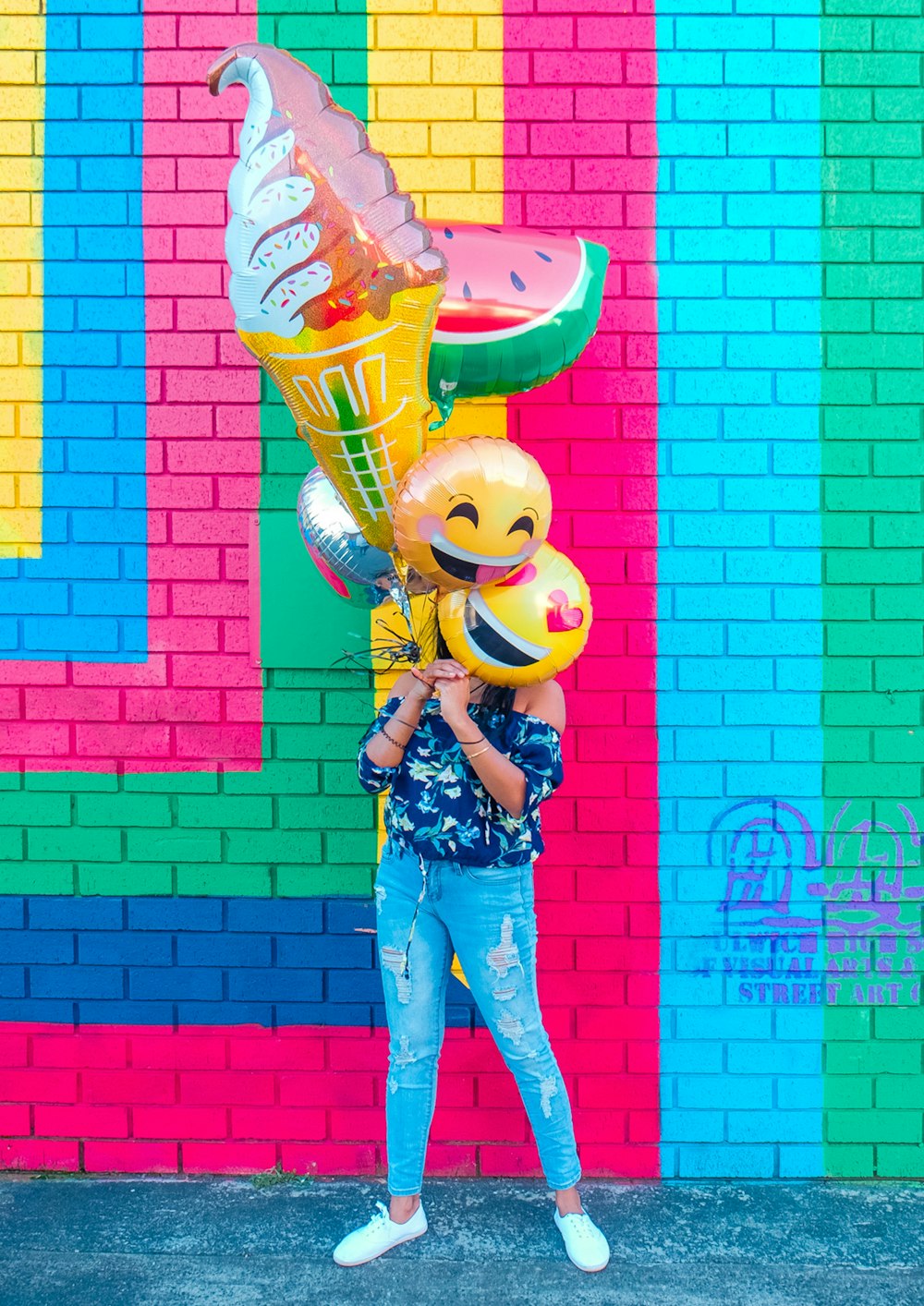 Frau bedeckt Gesicht mit verschiedenen Luftballons