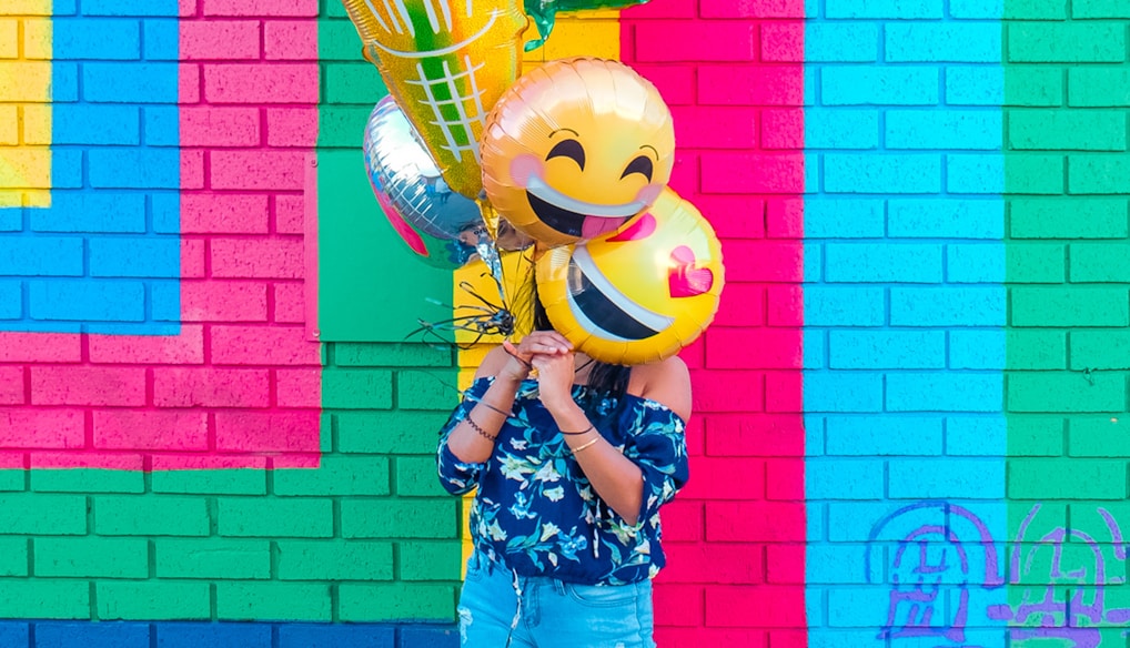 woman covering face with assorted ballons