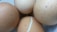 Four brown eggs are placed close together. One egg has a visible crack with egg white seeping out slightly. The eggs have subtle texture variations on the surface.