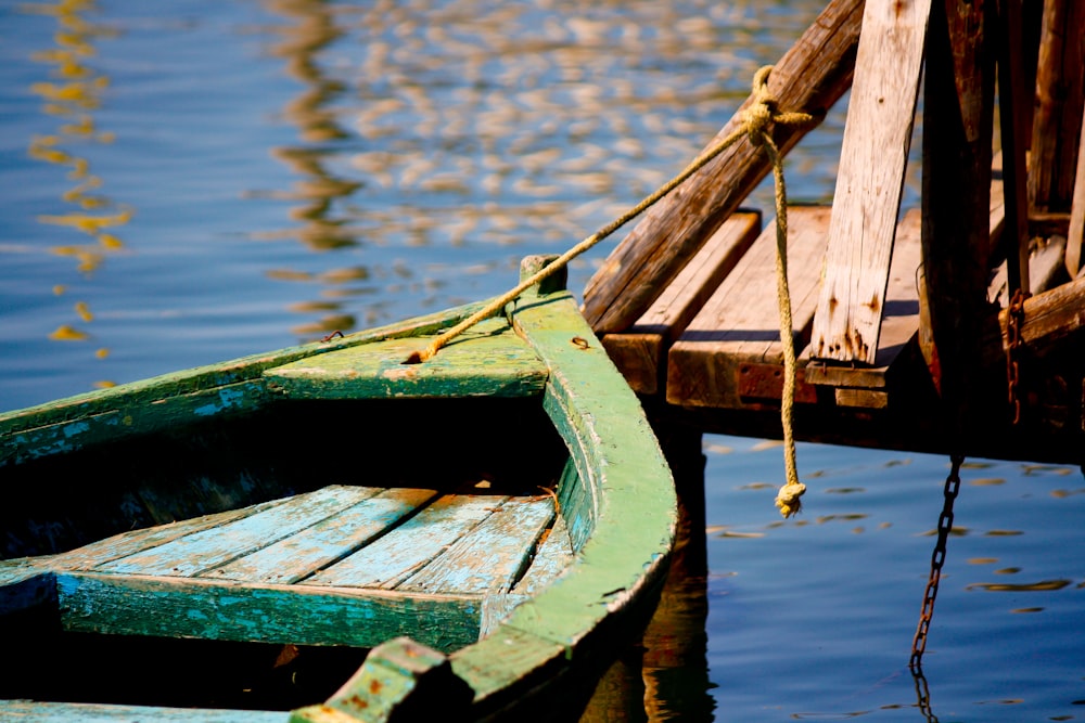 green wooden boat beside the docking pier