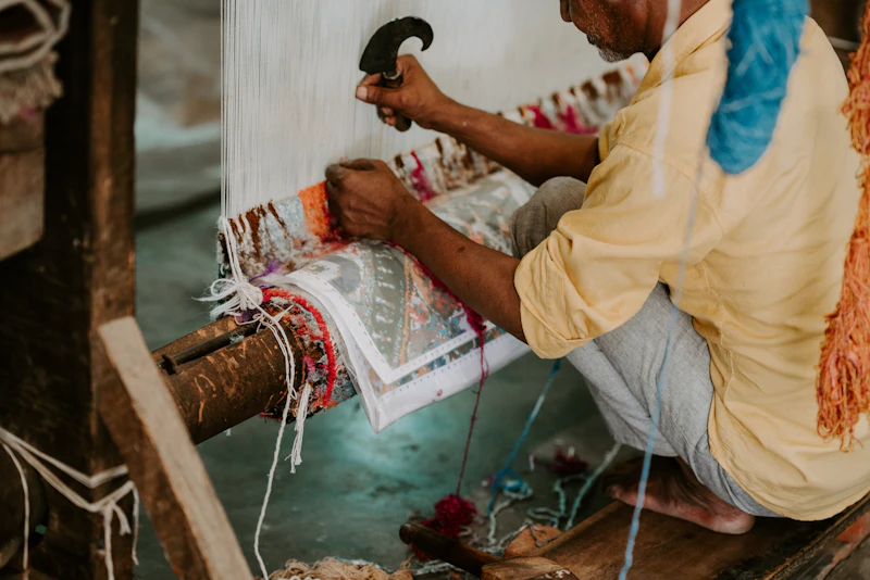 A weaver knotting a hand-knotted rug on a loom in Jaipur, India